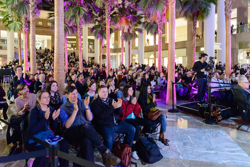 An enthusiastic audience seated in the outdoor space at Arts Brookfield